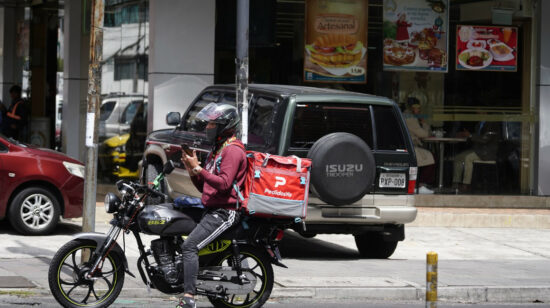 Un repartidor de delivery frente a un local de comida rápida, en el centro norte de Quito, enero de 2023. 
