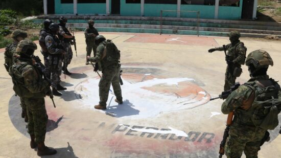 Un grupo de policías y militares borran un tigre de Los Tiguerones en el piso de una cancha deportiva en Esmeraldas, en abril del 2023. 